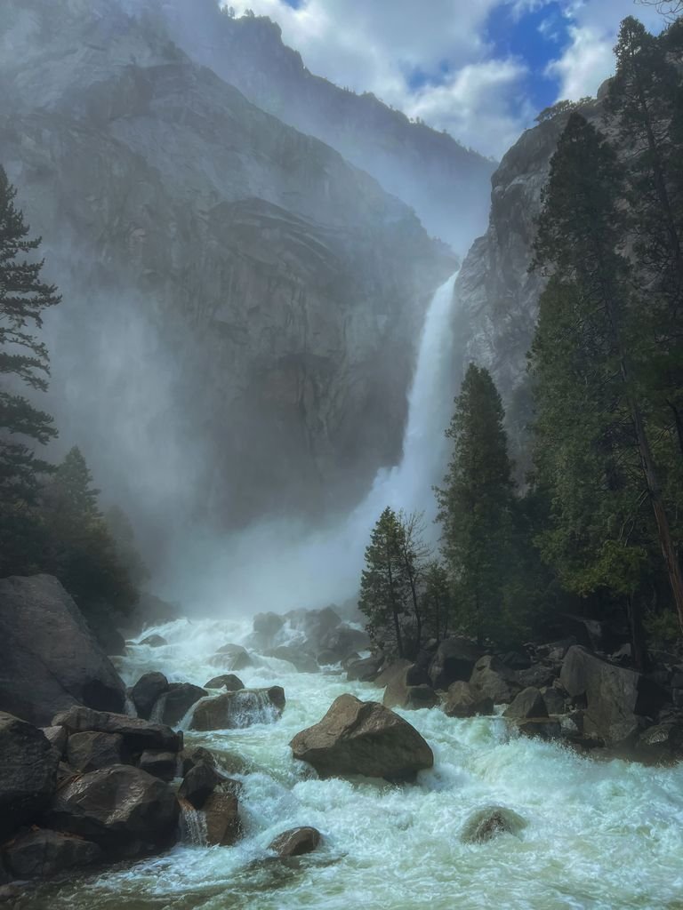 Breathtaking waterfall cascading down a misty mountain amidst lush greenery.