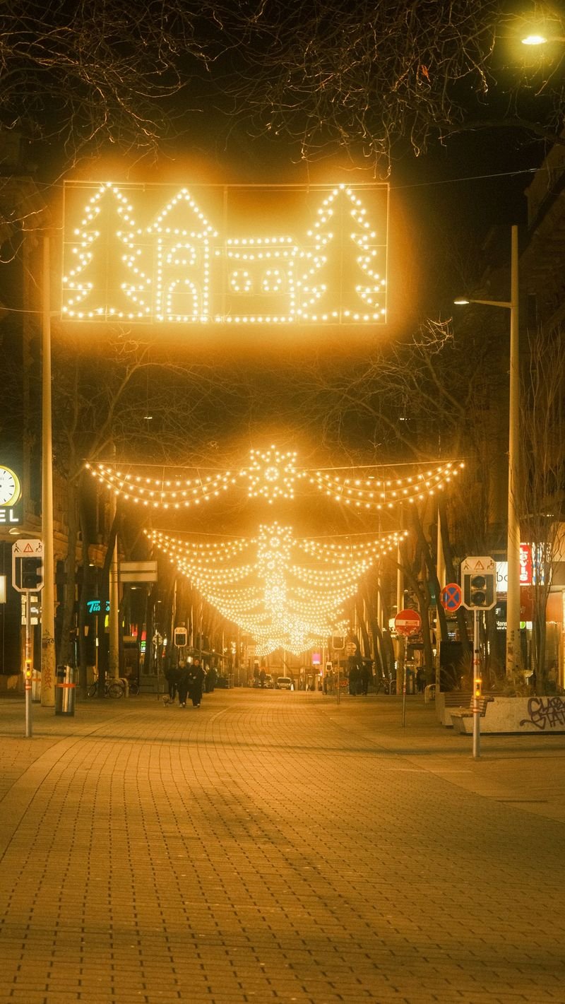 Street at night with illuminated holiday light displays strung overhead